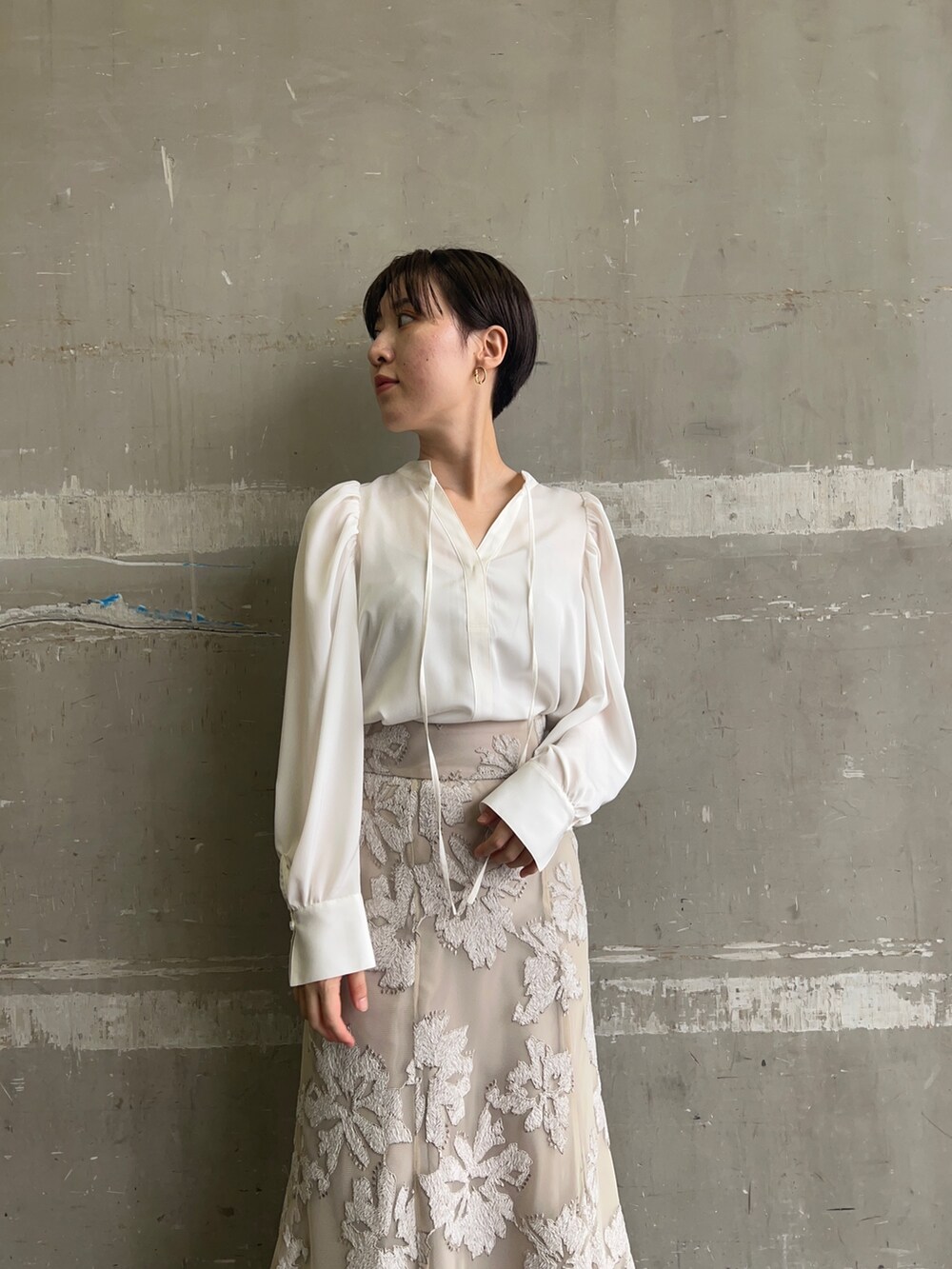 ベージュ系のスカート、ホワイト系のシャツ/ブラウス、ゴールド系のピアス(両耳用)を着用したレディースの秋コーディネートの3枚目の写真