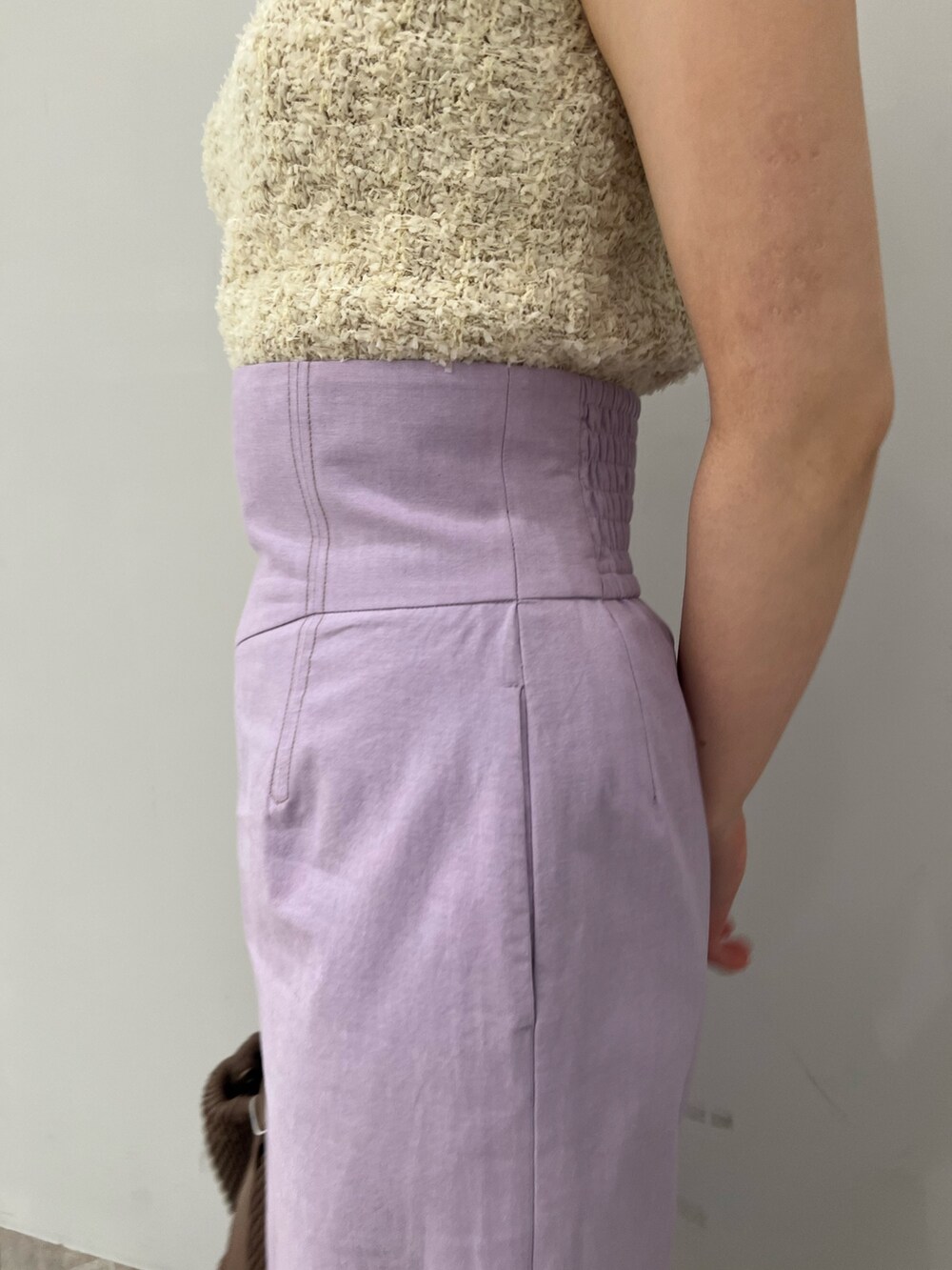 ホワイト系のハンドバッグ、ホワイト系のニット/セーター、パープル系のスカートを着用したレディースの春コーディネートの5枚目の写真