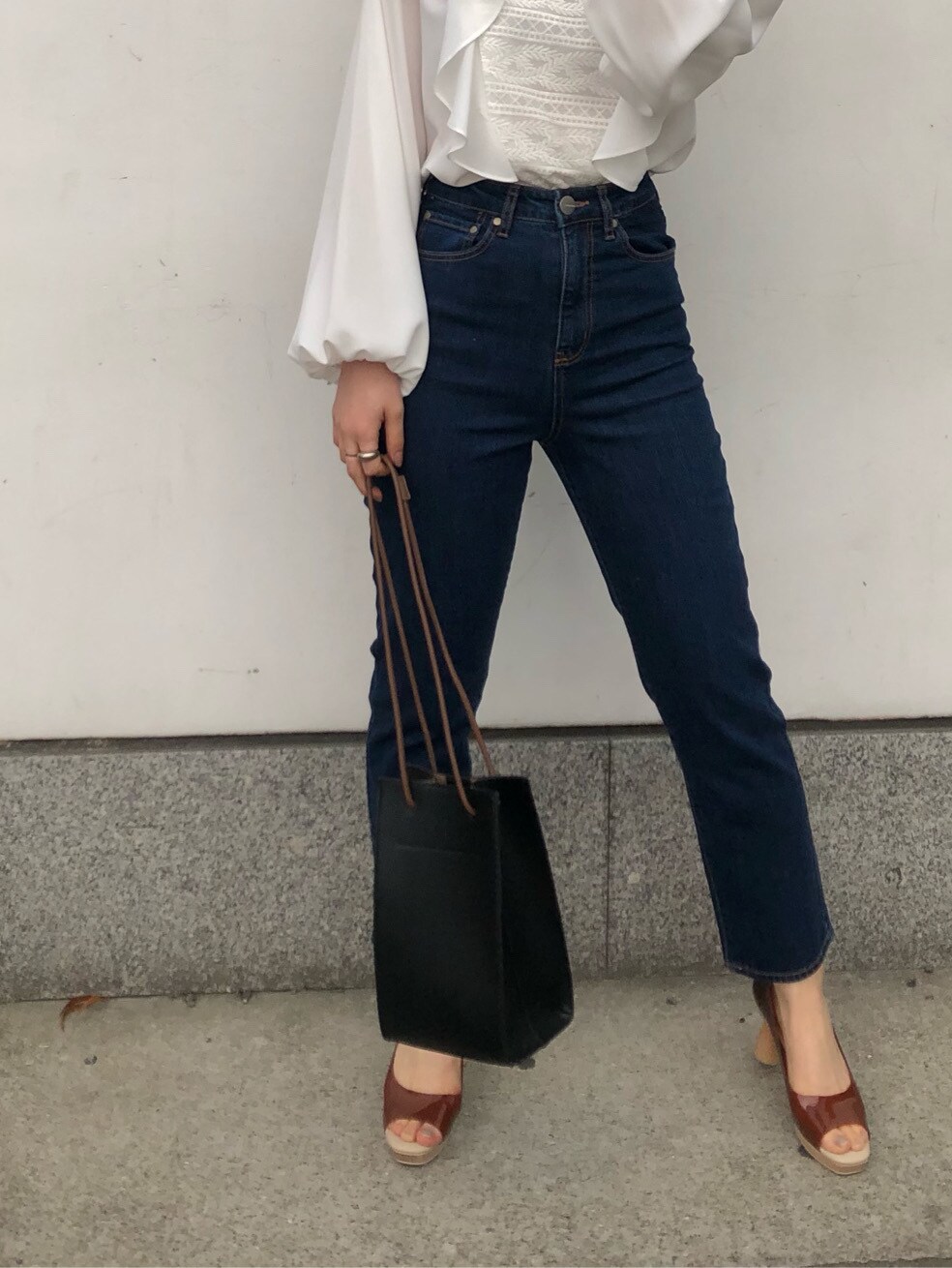 ブルー系のデニムパンツ、ブラック系のハンドバッグ、ブラウン系のパンプスを着用したレディースの春コーディネートの5枚目の写真