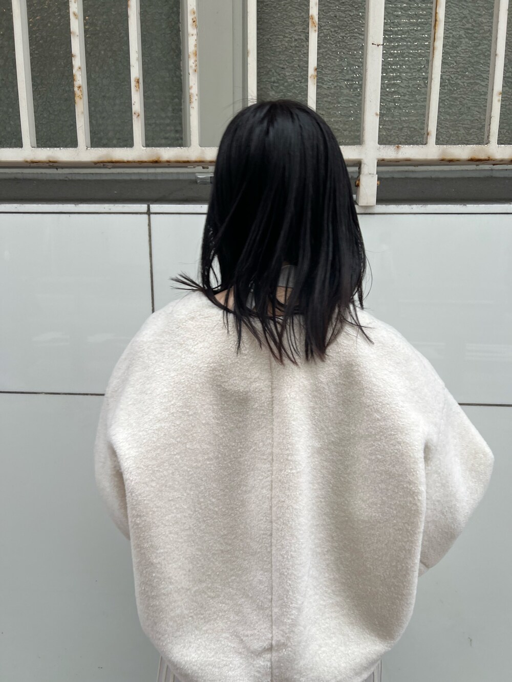 ホワイト系のブルゾン、グレー系のワンピース、ホワイト系のハンドバッグを着用したレディースの冬コーディネートの6枚目の写真