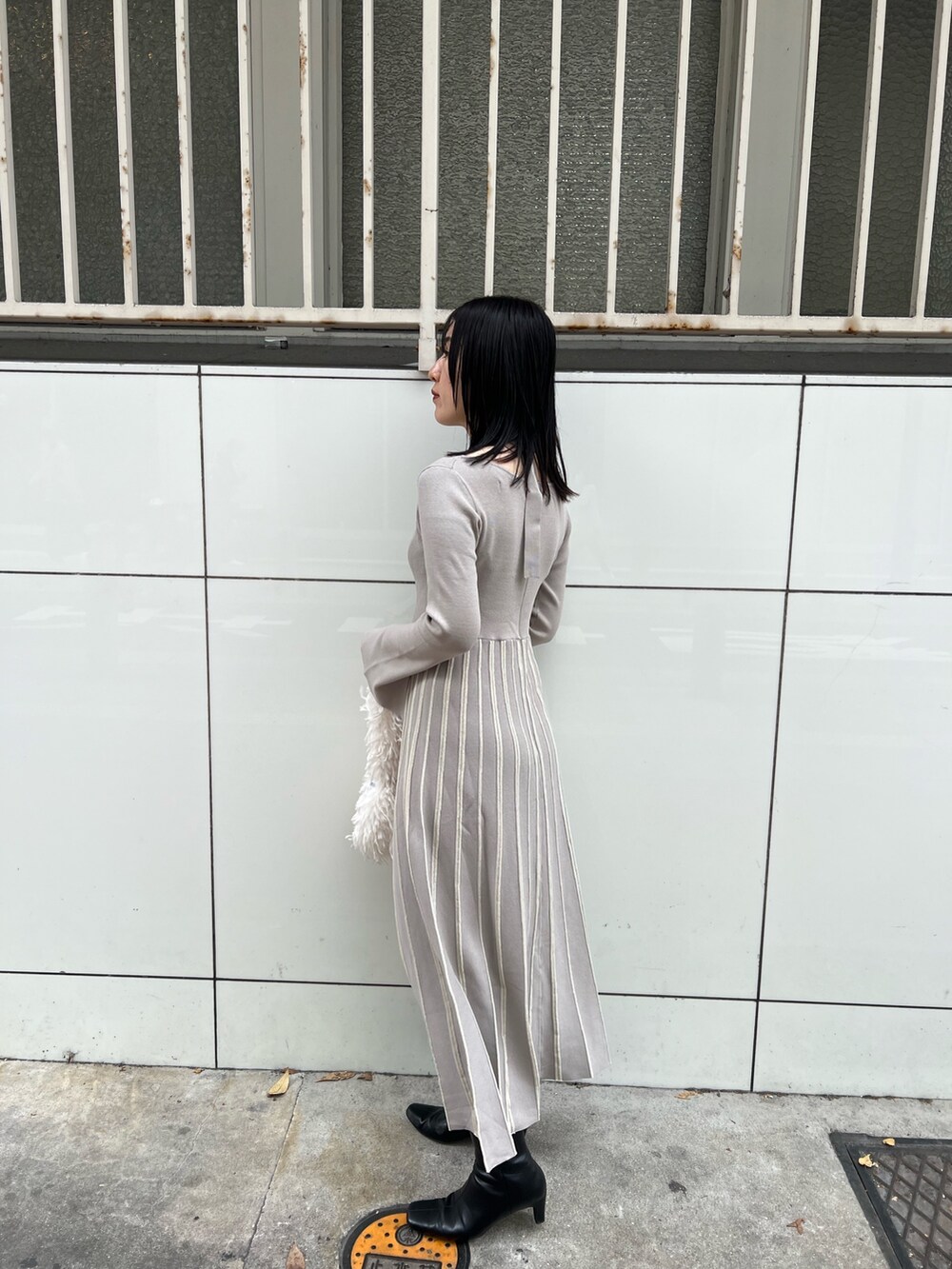 ホワイト系のブルゾン、グレー系のワンピース、ホワイト系のハンドバッグを着用したレディースの冬コーディネートの9枚目の写真