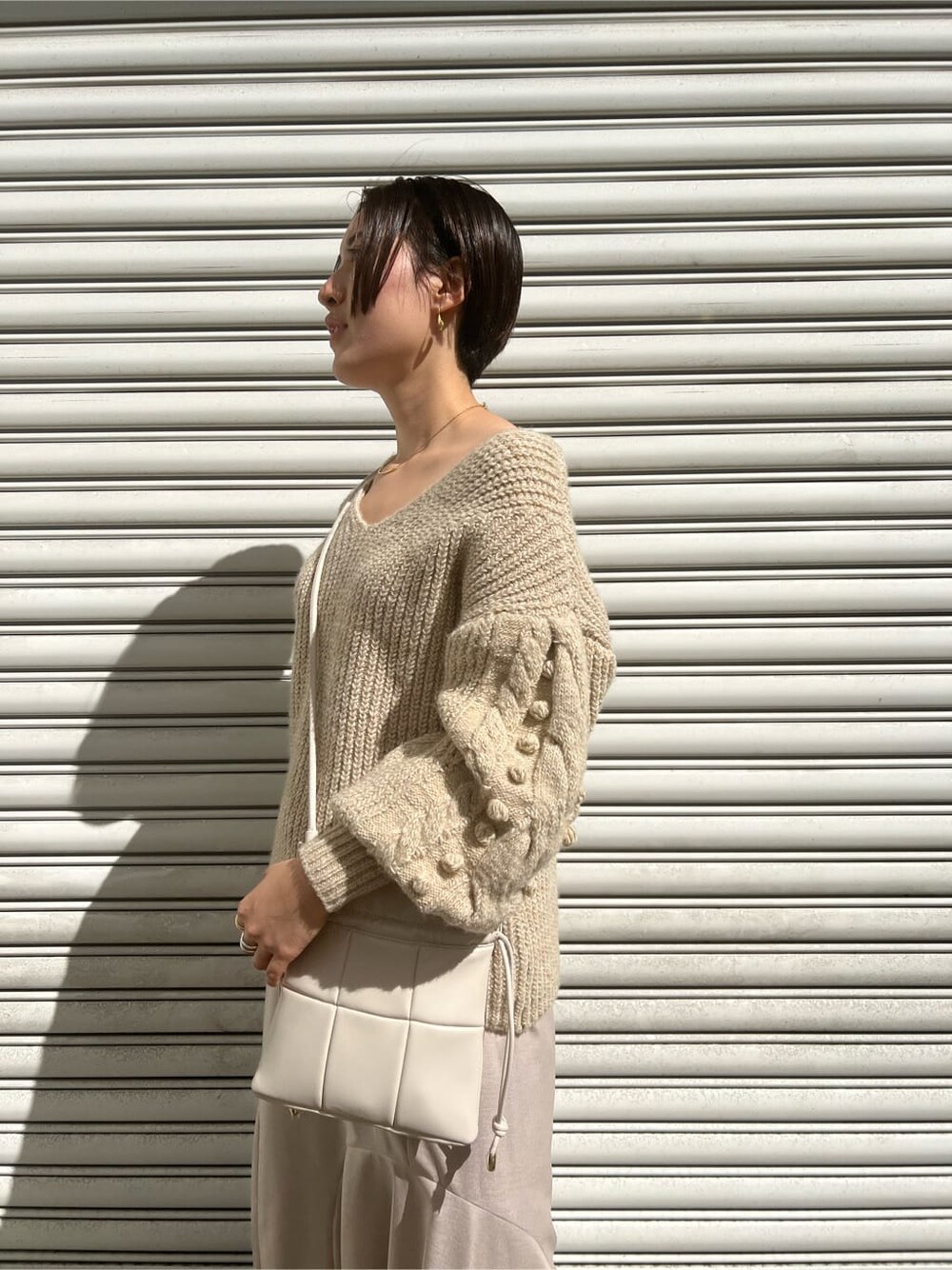 ベージュ系のブーツ、ホワイト系のニット/セーター、グレー系のスカートを着用したレディースの秋コーディネートの5枚目の写真