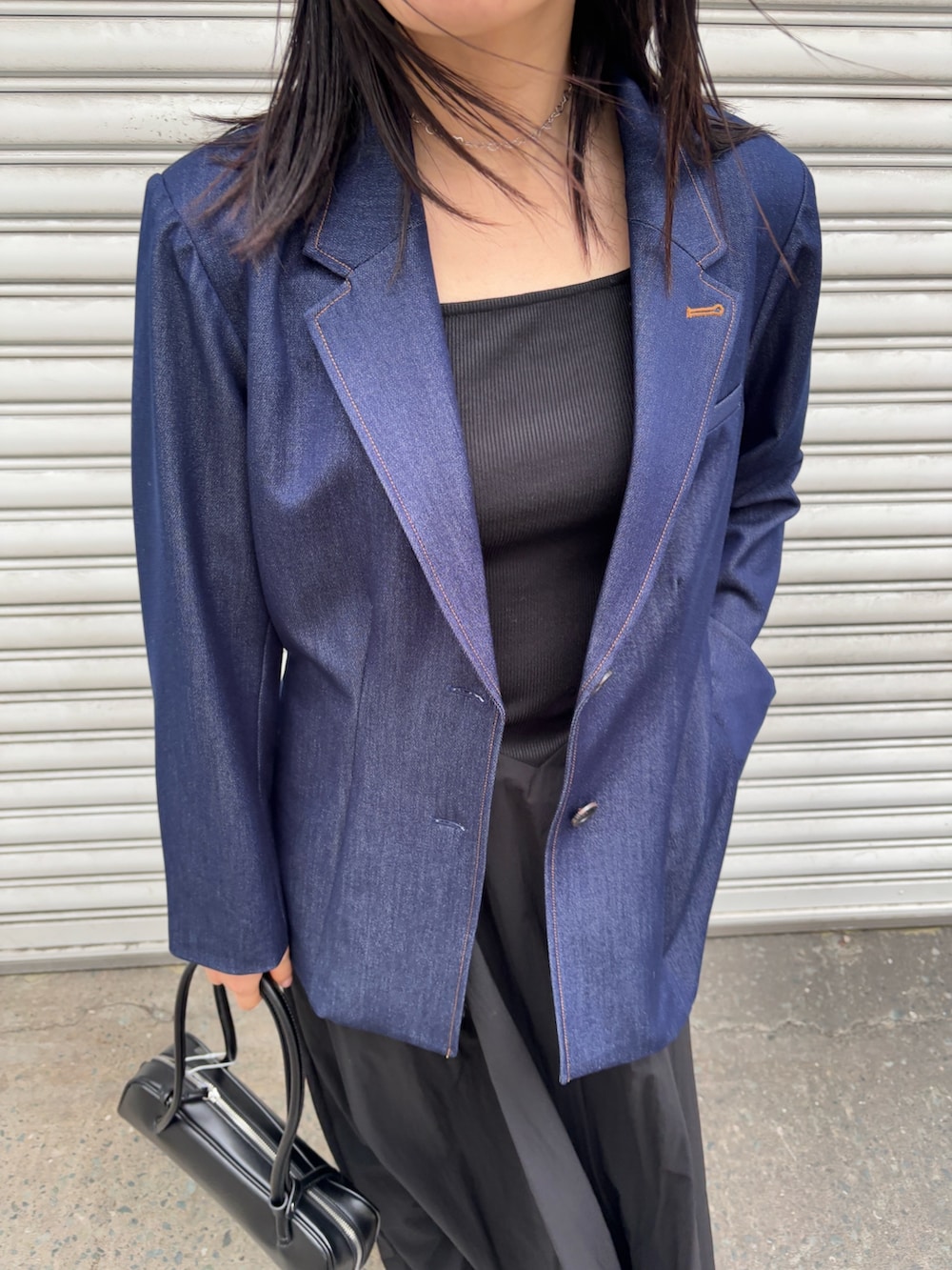 ブラック系のワンピース、ブルー系のテーラードジャケット、グレー系のスニーカーを着用したレディースの冬コーディネートの3枚目の写真