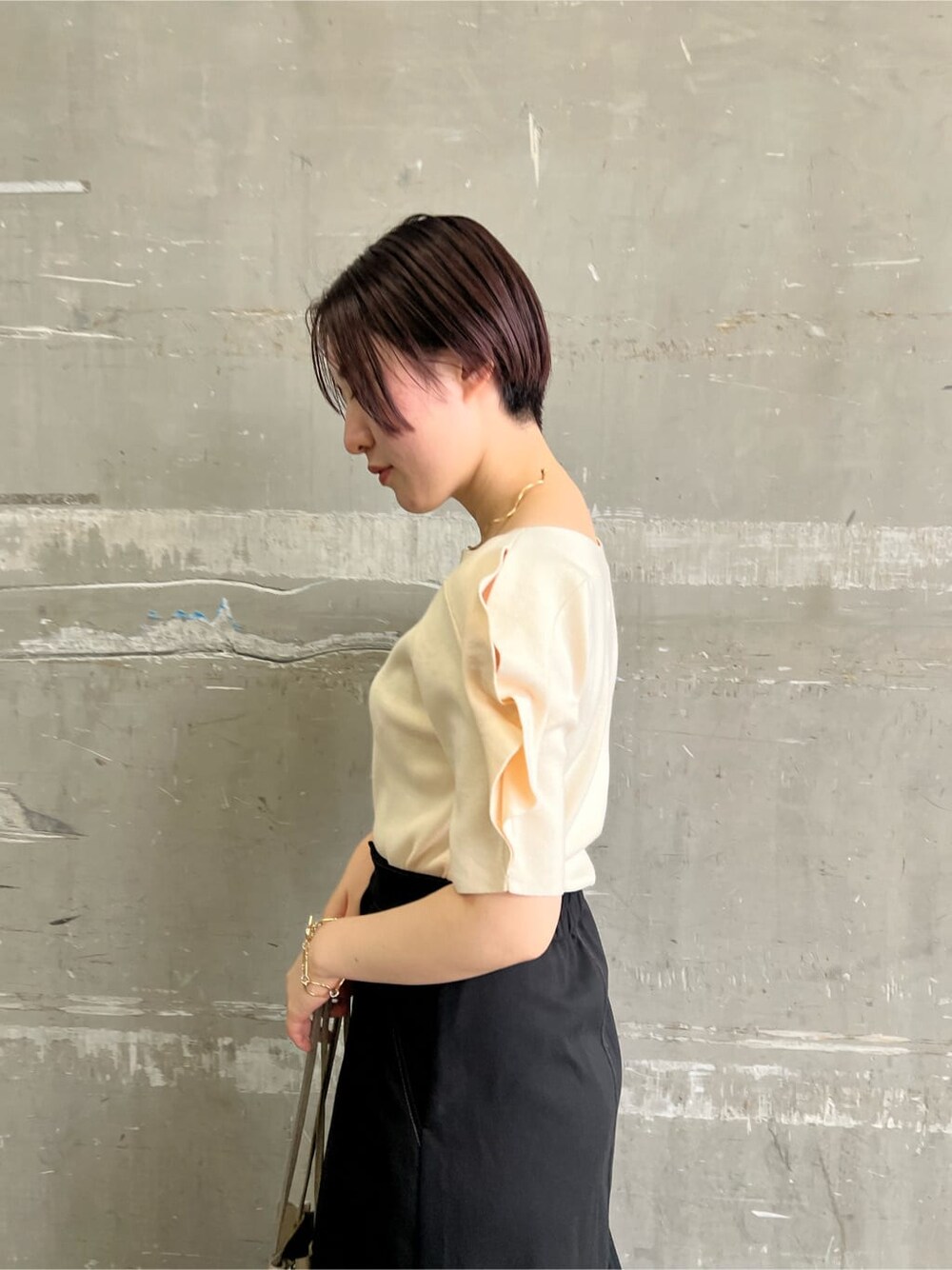 ベージュ系のハンドバッグ、ブラック系のスカート、ホワイト系のニット/セーターを着用したレディースの夏コーディネートの5枚目の写真