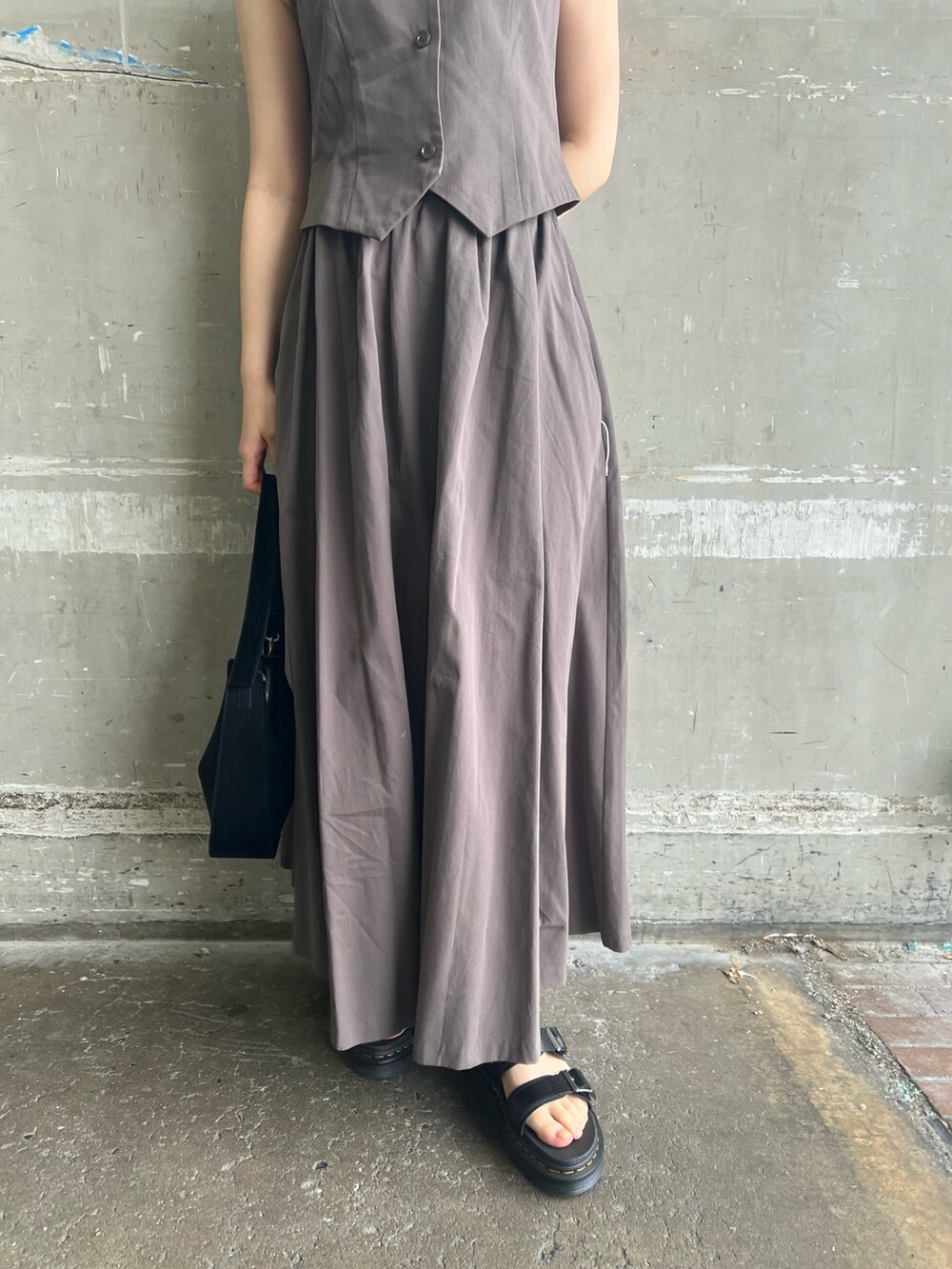 グレー系のワンピース、ブラック系のハンドバッグ、ブラック系のサンダルを着用したレディースの夏コーディネートの7枚目の写真