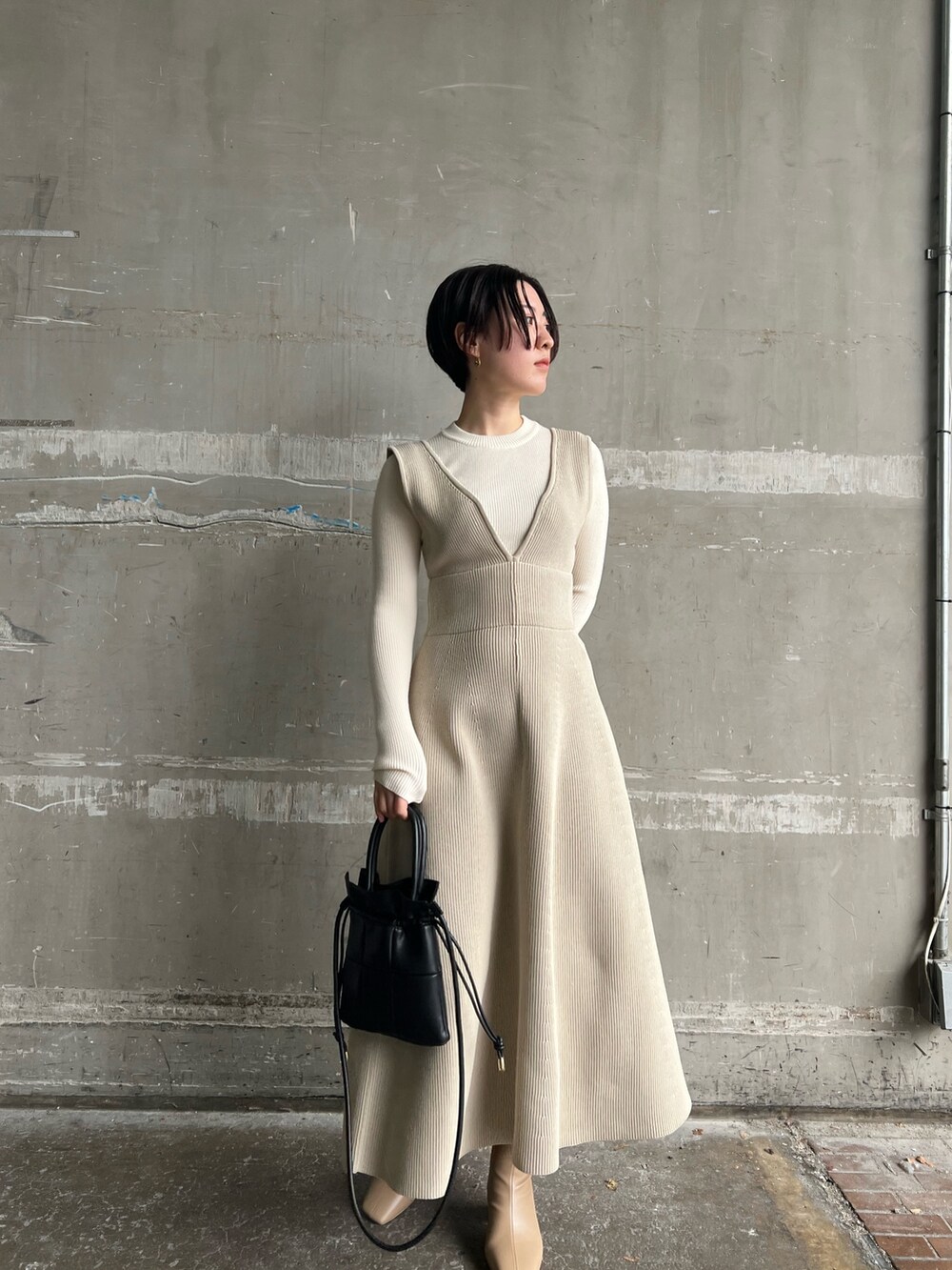 ベージュ系のブーツ、ブラック系のハンドバッグ、ホワイト系のニット/セーターを着用したレディースの秋コーディネートの3枚目の写真