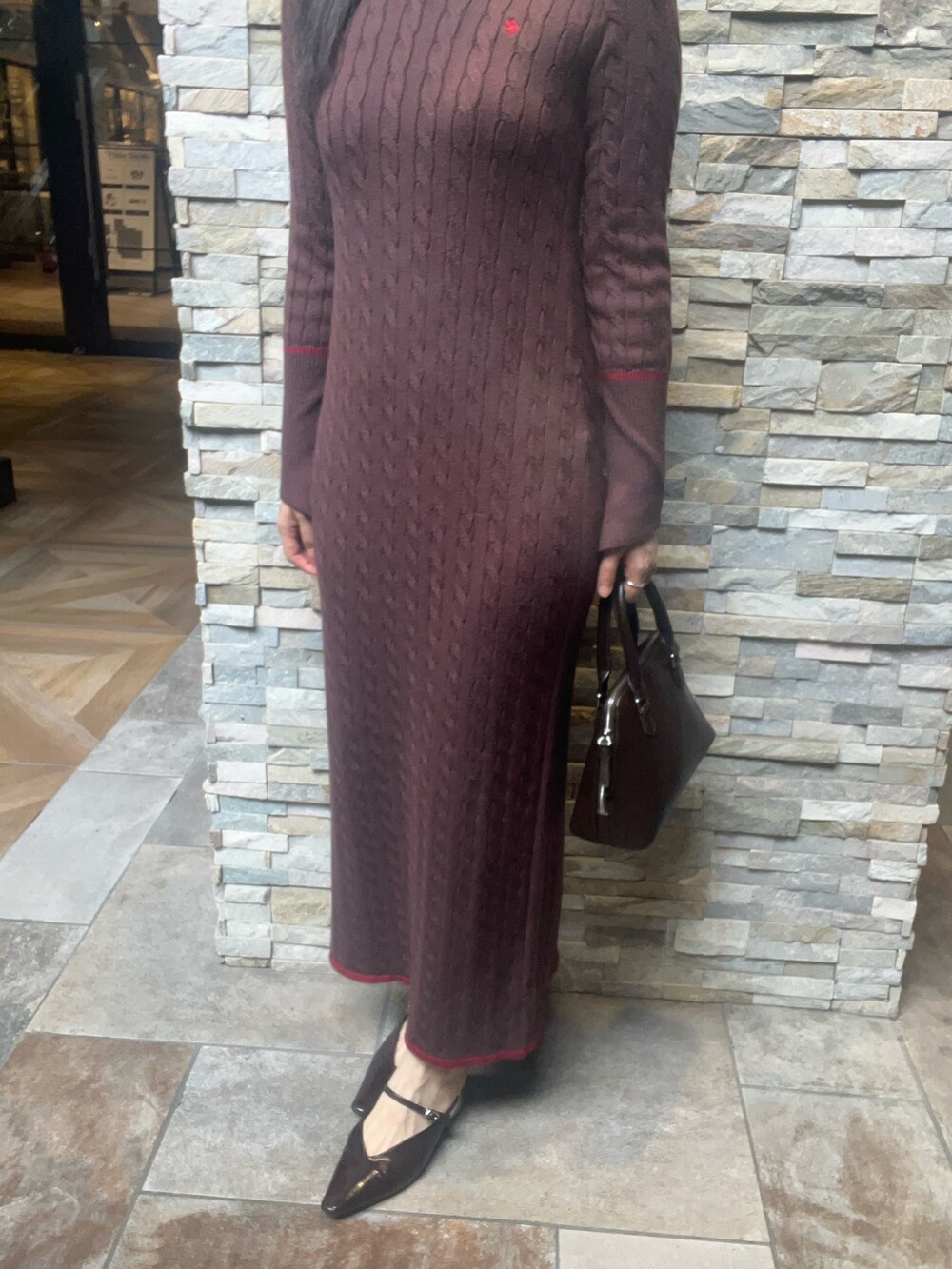 ブラウン系のワンピース、ブラウン系のボストンバッグ、ブラウン系のパンプスを着用したレディースの秋コーディネートの5枚目の写真