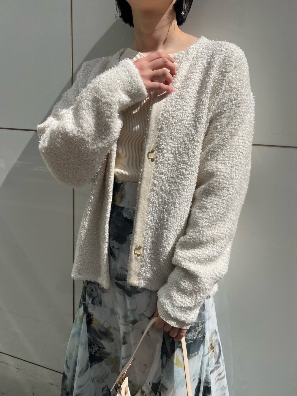 ホワイト系のパンプス、ベージュ系のハンドバッグ、ホワイト系のニット/セーターを着用したレディースの春コーディネートの4枚目の写真