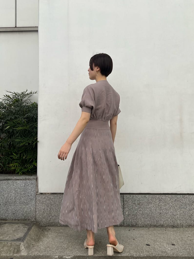 ホワイト系のノーカラーコート、グレー系のワンピース、ホワイト系のサンダルを着用したレディースの冬コーディネートの4枚目の写真