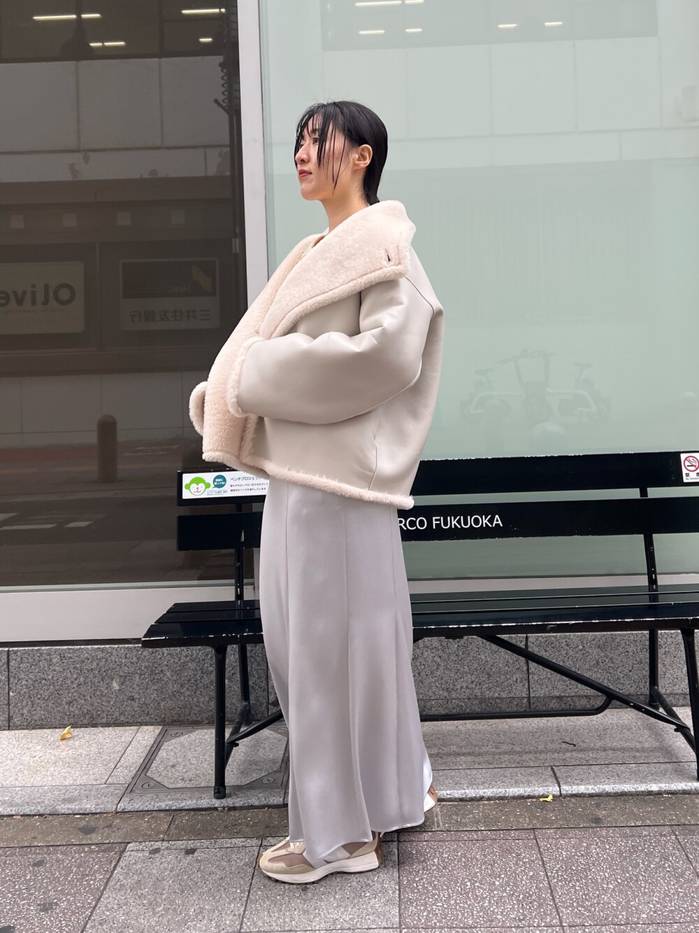 ホワイト系のムートンコート、グレー系のスカートを着用したレディースの冬コーディネートの2枚目の写真