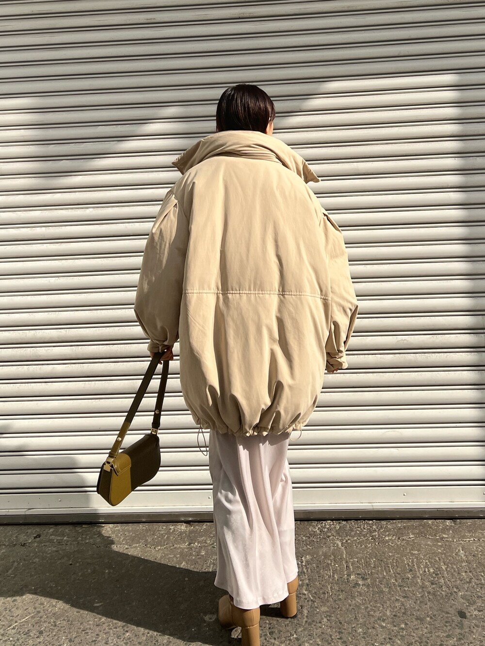 ブラウン系のショルダーバッグ、ベージュ系のブーツ、ベージュ系のダウンジャケット/コートを着用したレディースの冬コーディネートの2枚目の写真