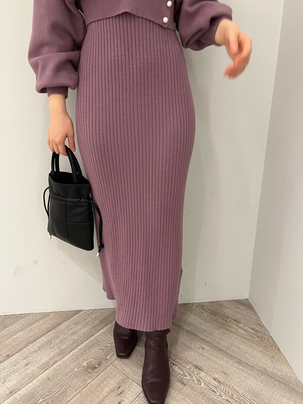 レッド系のブーツ、ブラック系のハンドバッグ、パープル系のワンピースを着用したレディースの冬コーディネートの7枚目の写真