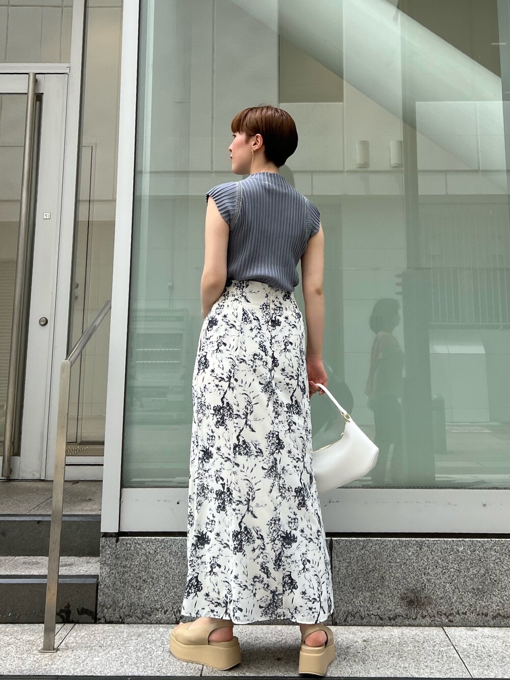 ベージュ系のサンダル、ブルー系のスカート、ホワイト系のハンドバッグを着用したレディースの夏コーディネートの2枚目の写真