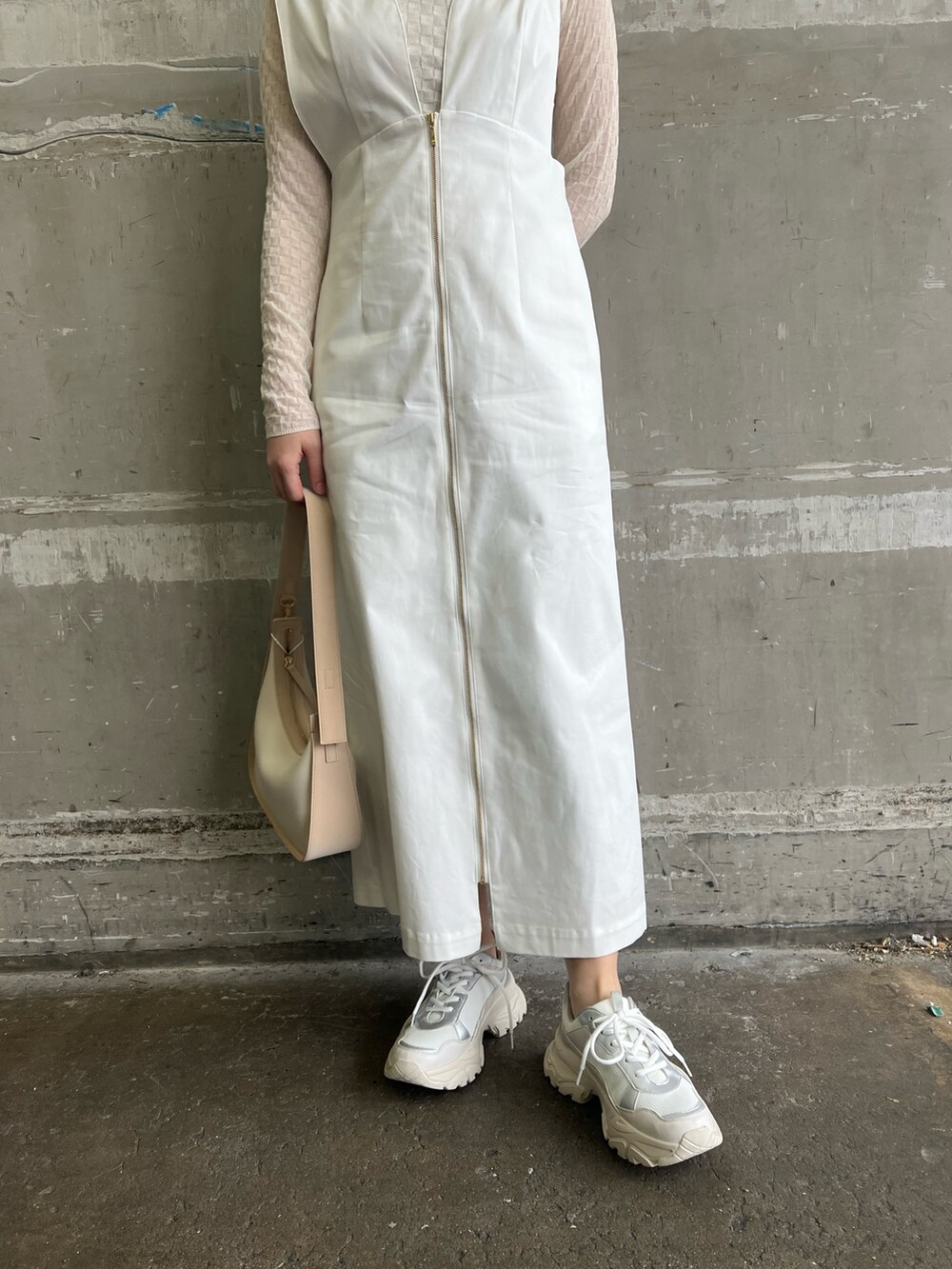 ホワイト系のジャンパースカート、ベージュ系のハンドバッグ、ホワイト系のTシャツ/カットソーを着用したレディースの春コーディネートの4枚目の写真