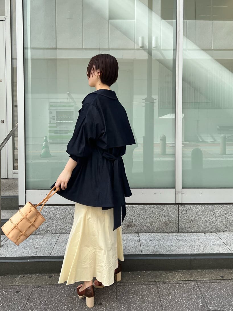 ブルー系のトレンチコート、ブラック系のワンピース、ブラウン系のパンプスを着用したレディースの春コーディネートの2枚目の写真