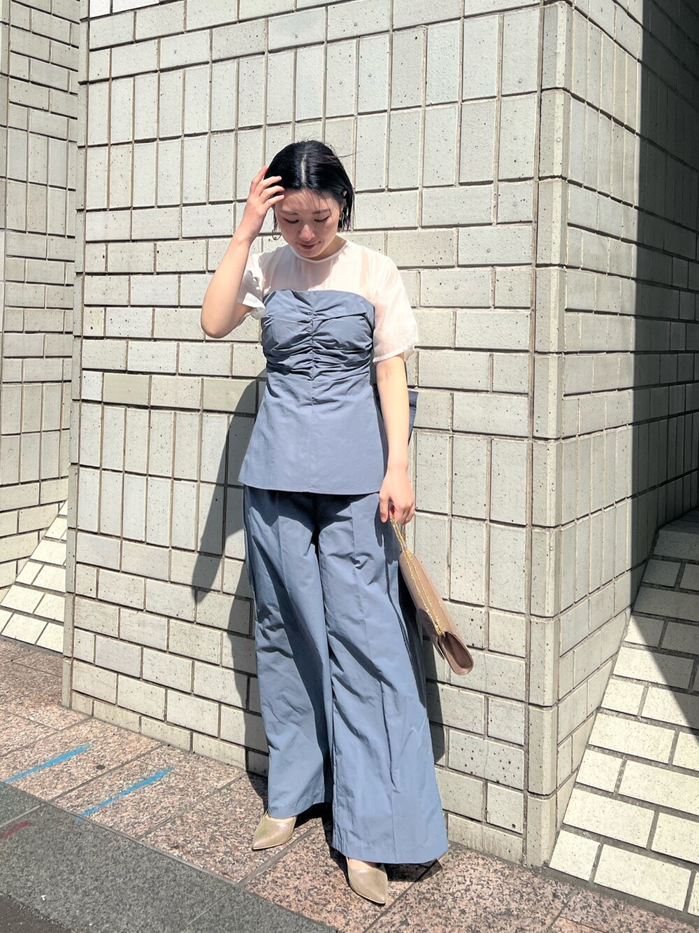 ゴールド系のパンプス、ゴールド系のハンドバッグ、ブルー系のパンツドレスを着用したレディースの春コーディネートの3枚目の写真