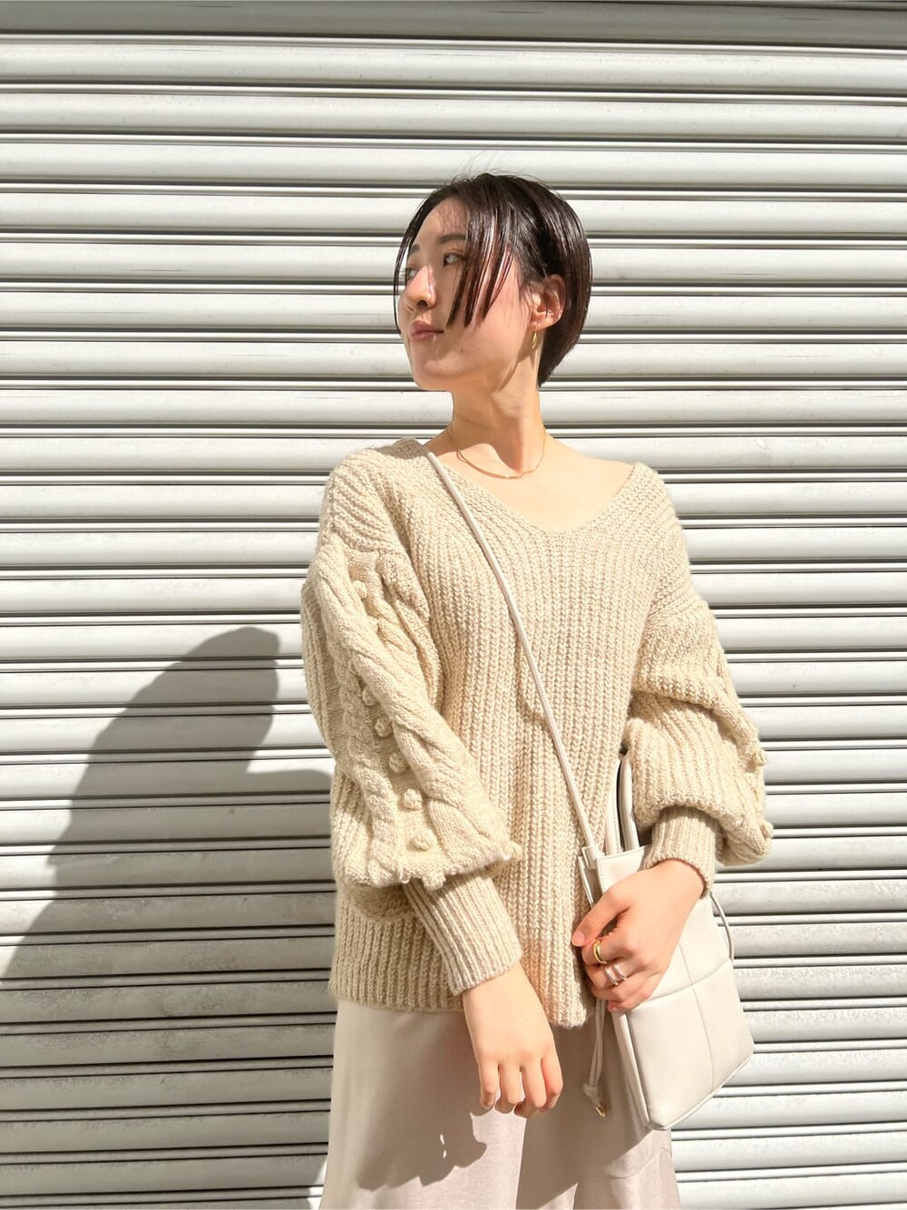 ベージュ系のブーツ、ホワイト系のニット/セーター、グレー系のスカートを着用したレディースの秋コーディネートの4枚目の写真