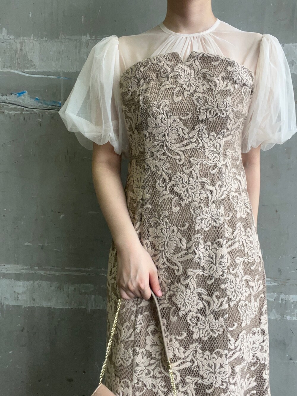 ベージュ系のドレス、ブラウン系のクラッチバッグ、ゴールド系のパンプスを着用したレディースの秋コーディネートの4枚目の写真