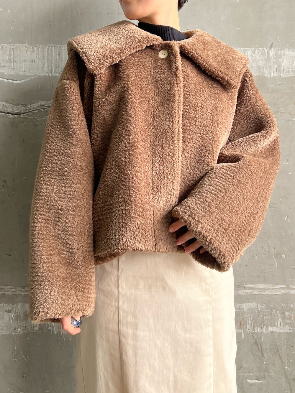 レッド系のブーツ、ホワイト系のスカート、ブラウン系のブルゾンを着用したレディースの冬コーディネートの8枚目の写真