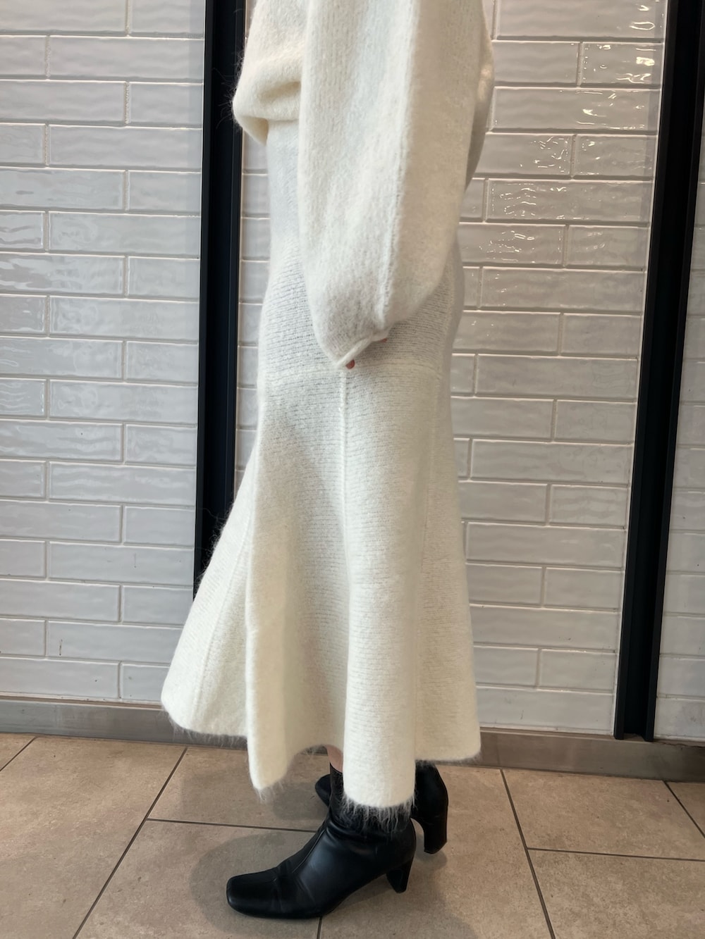 ホワイト系のスカート、ホワイト系のニット/セーター、ホワイト系のショルダーバッグを着用したレディースの秋コーディネートの6枚目の写真