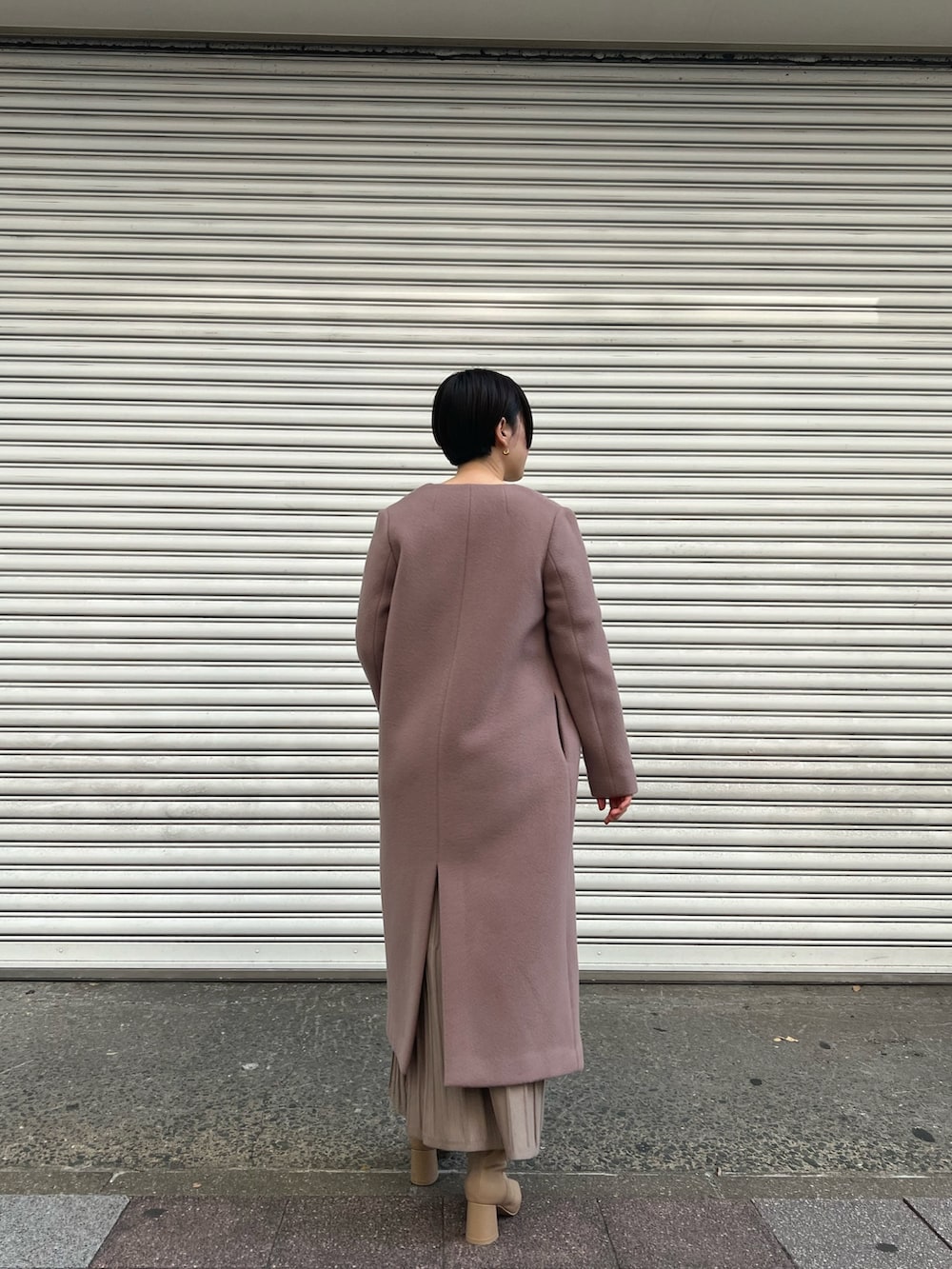 ピンク系のノーカラーコート、ホワイト系のワンピース、ベージュ系のブーツを着用したレディースの秋コーディネートの3枚目の写真