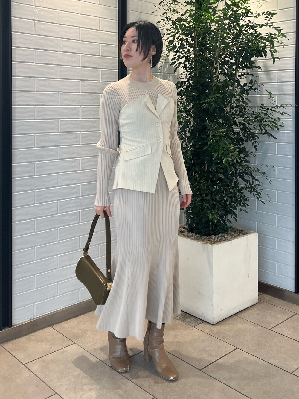 ベージュ系のブーツ、ベージュ系のワンピース、ブラウン系のショルダーバッグを着用したレディースの冬コーディネートの2枚目の写真