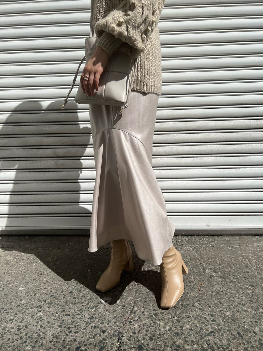 ベージュ系のブーツ、ホワイト系のニット/セーター、グレー系のスカートを着用したレディースの秋コーディネートの7枚目の写真
