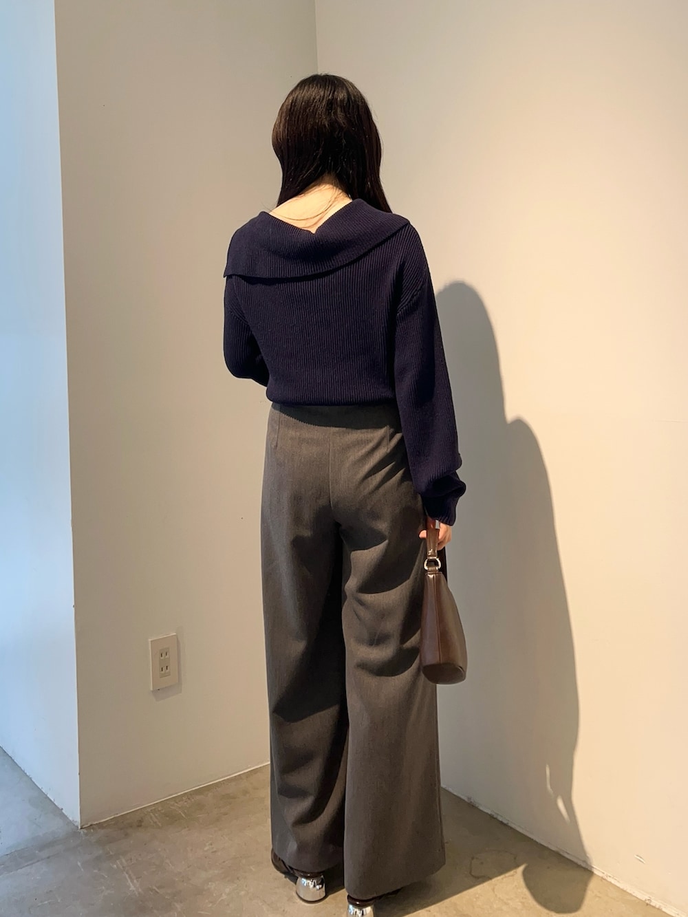 イエロー系のハンドバッグ、ブルー系のニット/セーター、ブラウン系のパンプスを着用したレディースの秋コーディネートの3枚目の写真