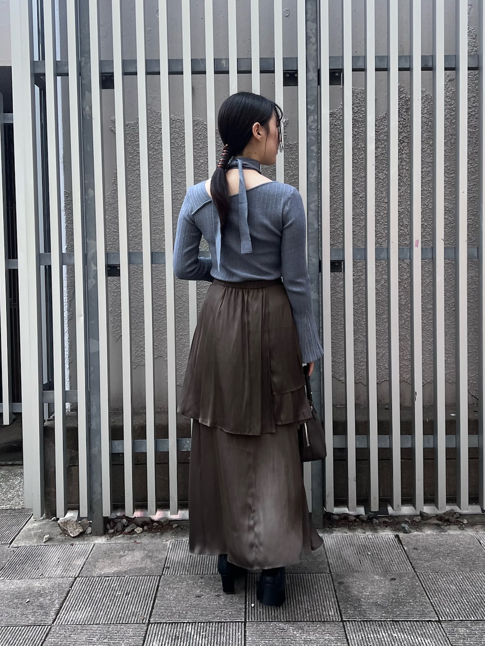 ブルー系のニット/セーター、ブラウン系のスカート、ブラック系のブーツを着用したレディースの秋コーディネートの3枚目の写真