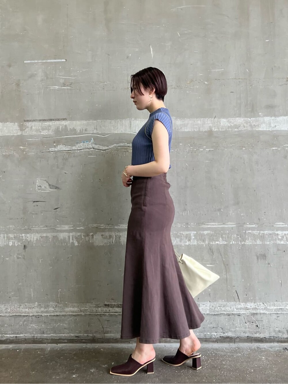 ホワイト系のハンドバッグ、レッド系のサンダル、ブラウン系のスカートを着用したレディースの夏コーディネートの2枚目の写真