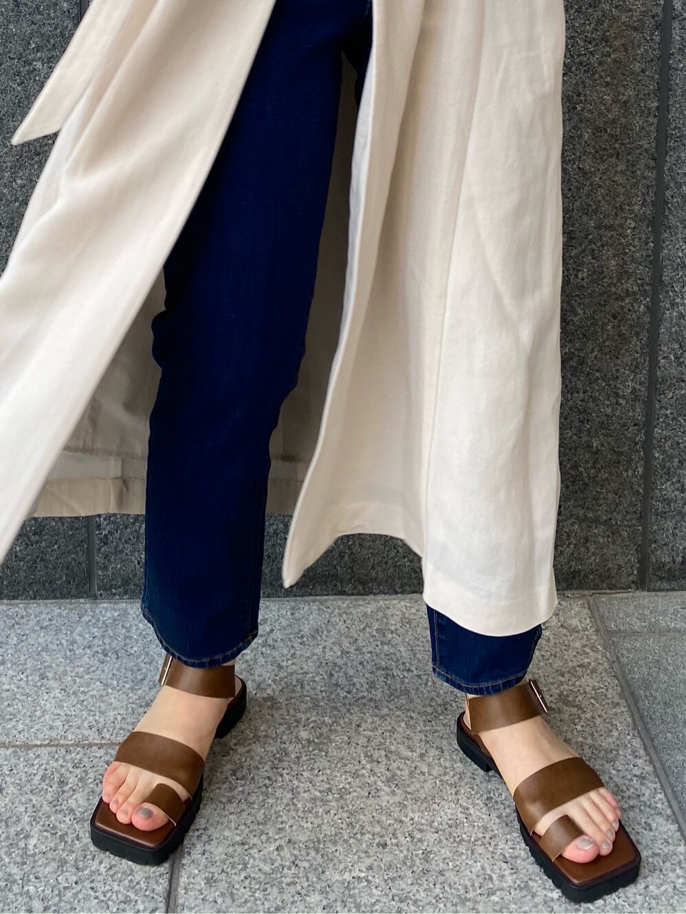 ブルー系のデニムパンツ、ブラウン系のサンダル、ベージュ系のワンピースを着用したレディースの春コーディネートの5枚目の写真