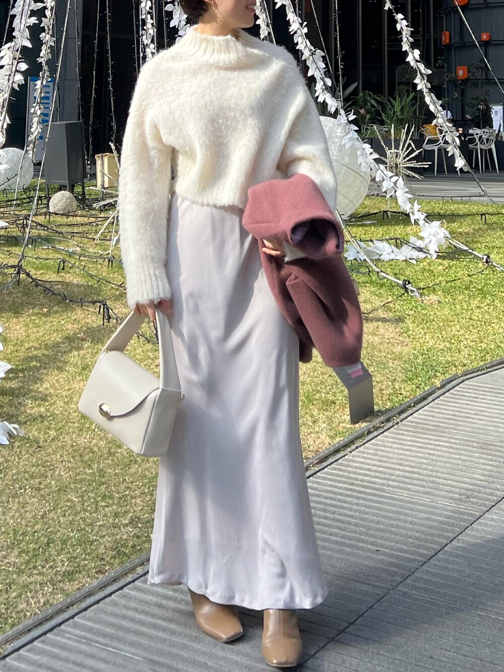 ホワイト系のスカート、ホワイト系のハンドバッグ、ピンク系のカーディガン/ボレロを着用したレディースの冬コーディネートの3枚目の写真