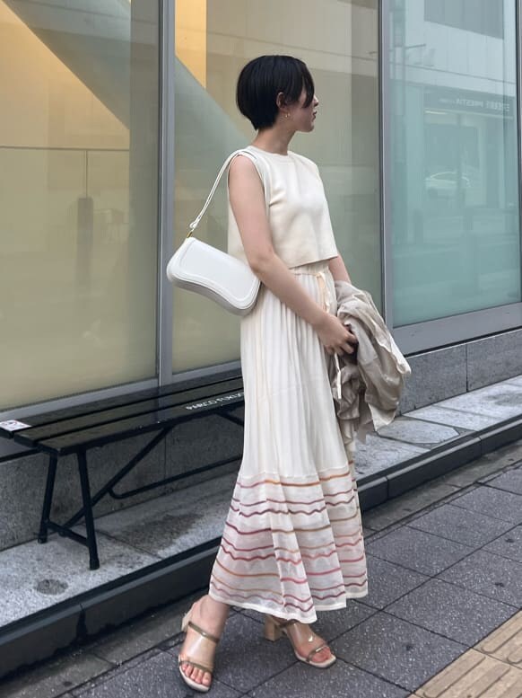 ホワイト系のワンピース、ホワイト系のショルダーバッグ、ゴールド系のピアス（両耳用）を着用したレディースの夏コーディネートの2枚目の写真