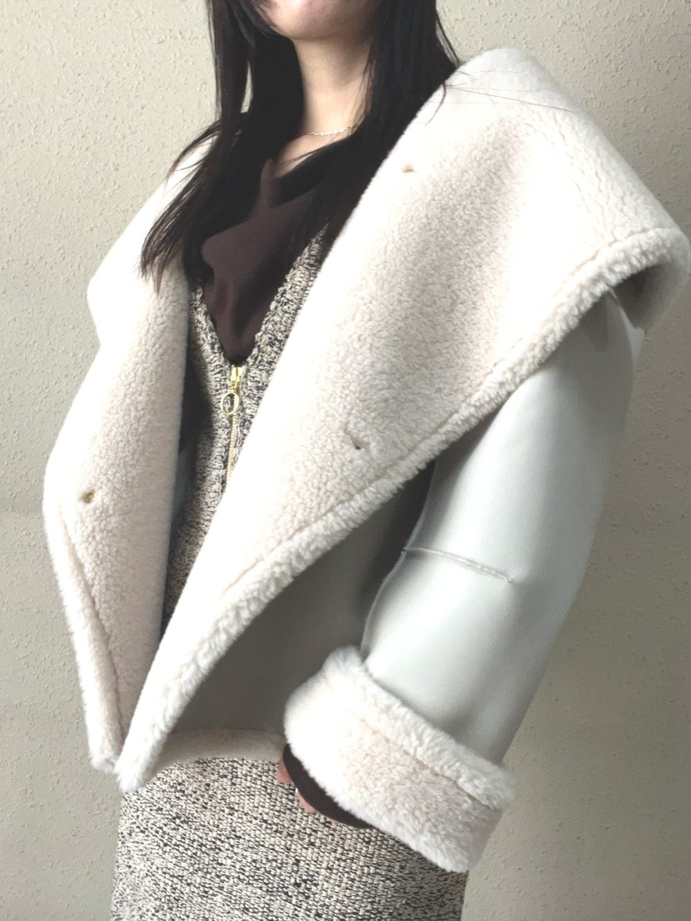 ブラウン系のブーツ、ホワイト系のムートンコート、ベージュ系のジャンパースカートを着用したレディースの秋コーディネートの4枚目の写真