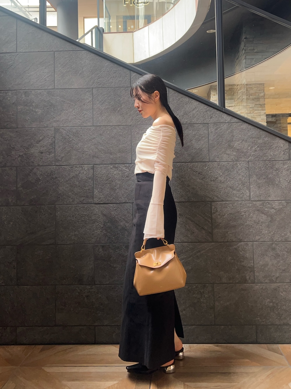 ホワイト系のTシャツ/カットソー、ブラック系のスカート、ブラウン系のパンプスを着用したレディースの秋コーディネートの2枚目の写真