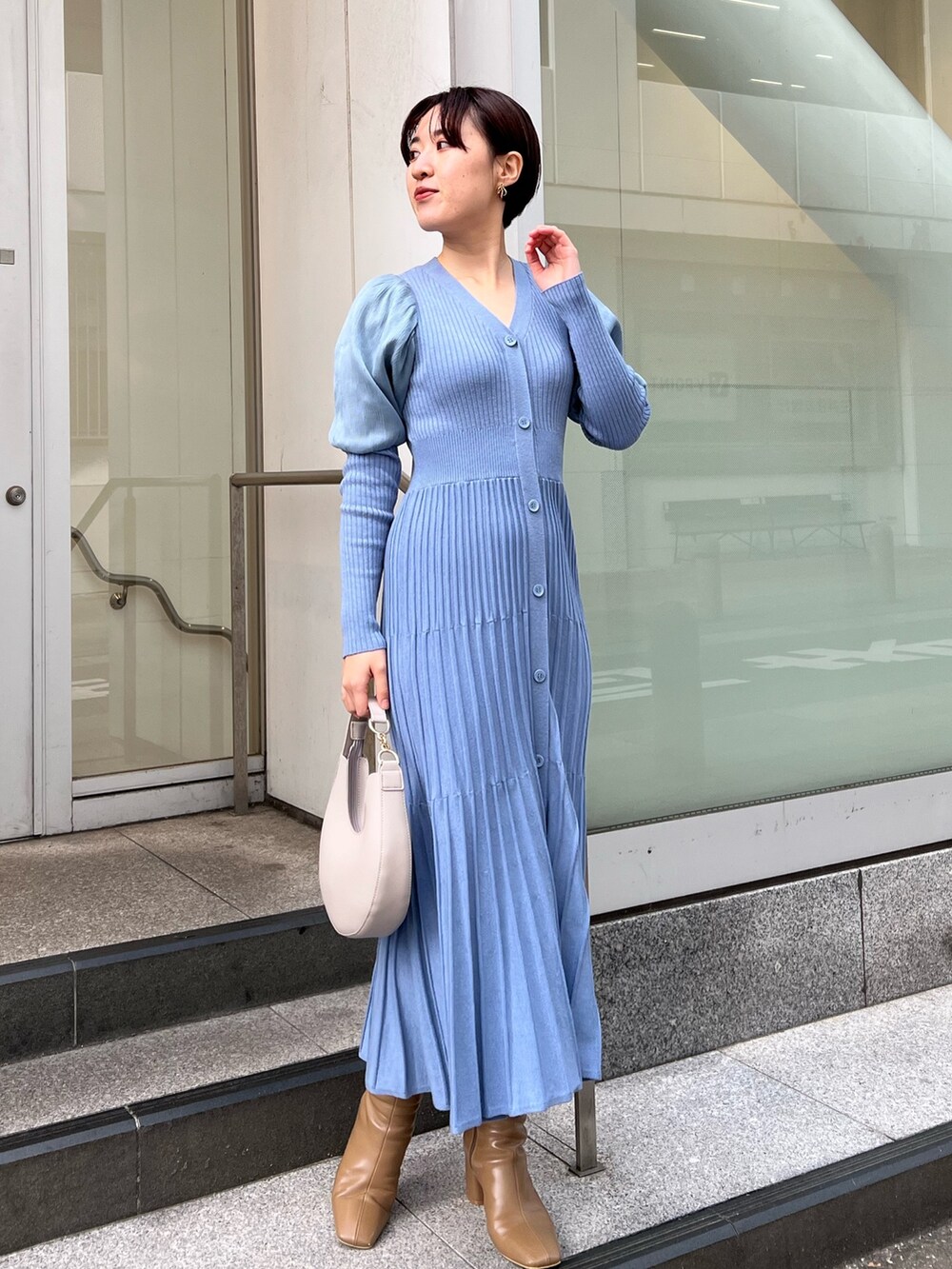 ベージュ系のブーツ、ホワイト系のハンドバッグ、ホワイト系のノーカラーコートを着用したレディースの冬コーディネートの5枚目の写真