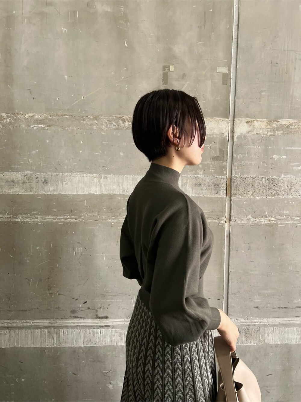 ベージュ系のブーツ、ベージュ系のハンドバッグ、ベージュ系のワンピースを着用したレディースの秋コーディネートの5枚目の写真