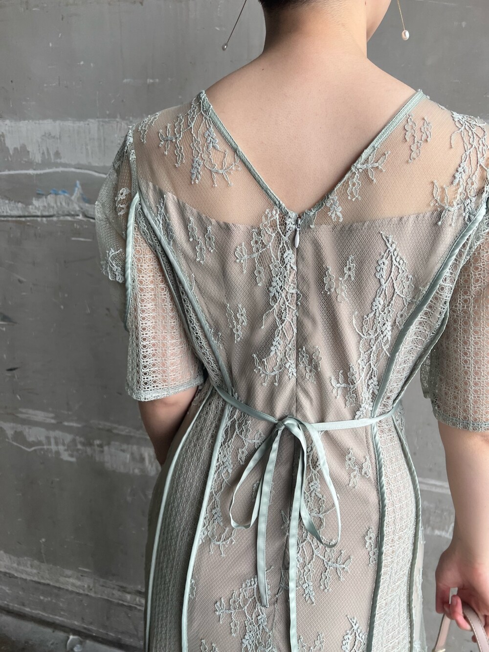 グリーン系のドレス、ベージュ系のパンプス、ベージュ系のクラッチバッグを着用したレディースの春コーディネートの6枚目の写真