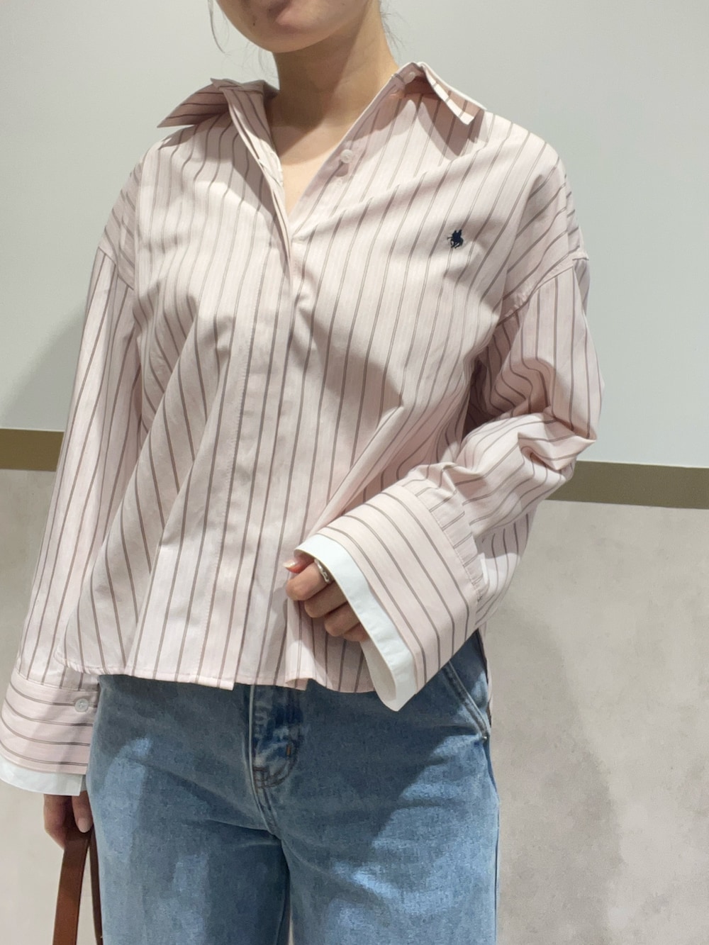 ピンク系のシャツ/ブラウス、ブルー系のデニムパンツ、ブラウン系のハンドバッグを着用したレディースの春コーディネートの4枚目の写真