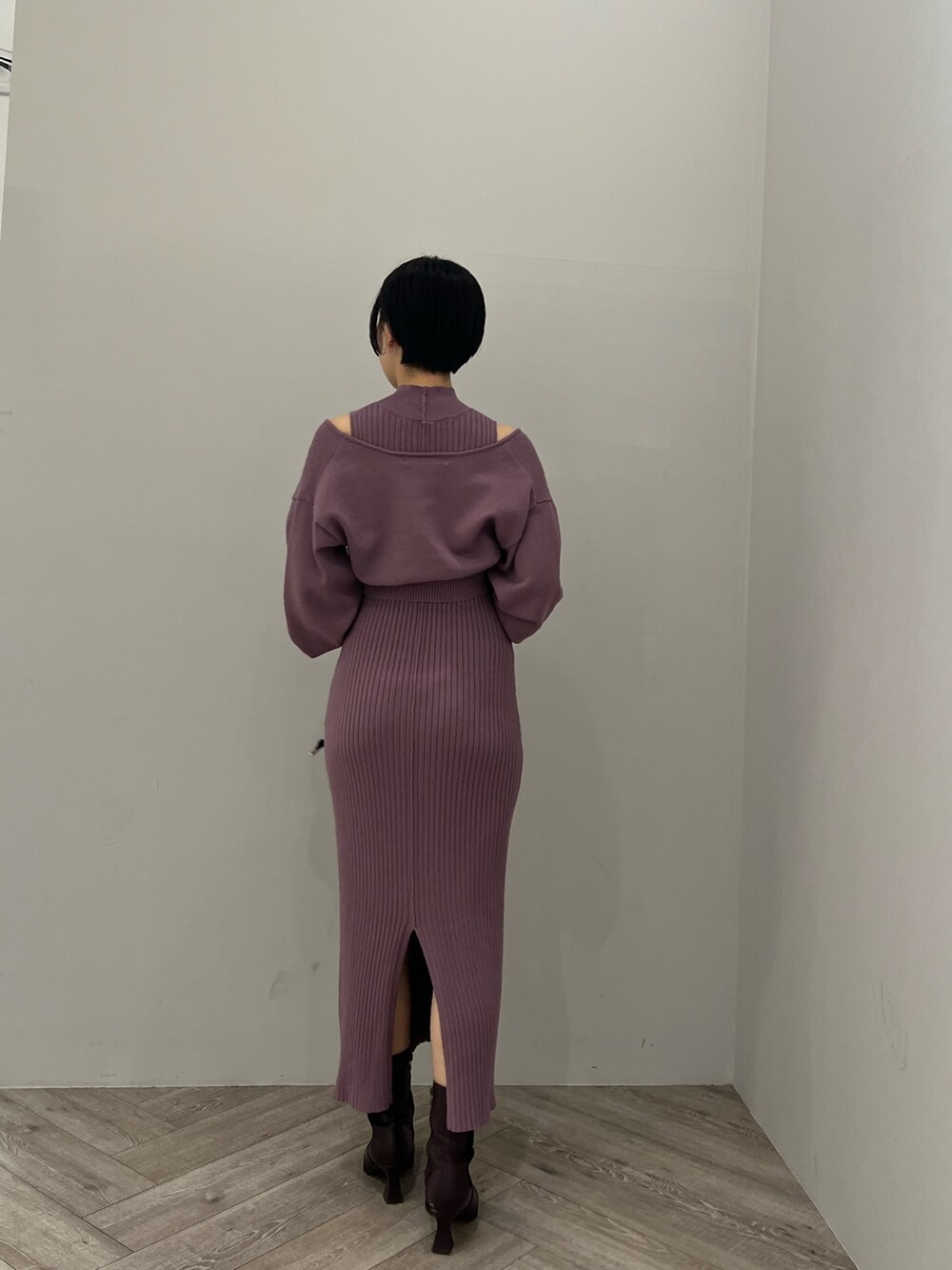 レッド系のブーツ、ブラック系のハンドバッグ、パープル系のワンピースを着用したレディースの冬コーディネートの3枚目の写真