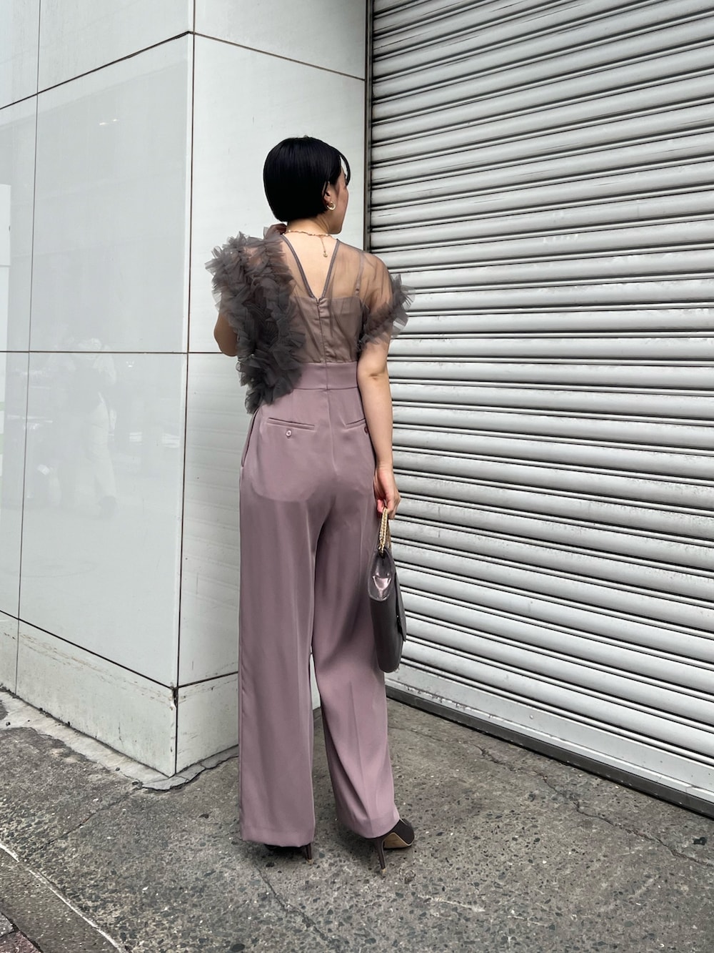 シルバー系のパンプス、ブラック系のチェスターコート、シルバー系のハンドバッグを着用したレディースの冬コーディネートの5枚目の写真