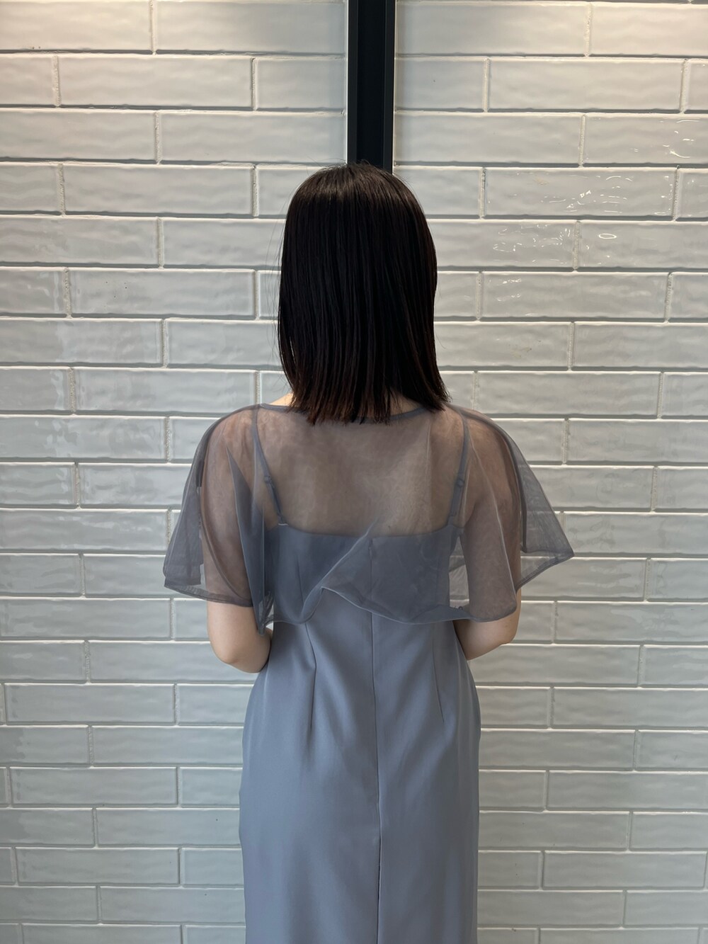 パープル系のドレス、ブラック系のクラッチバッグ、ブラック系のパンプスを着用したレディースの秋コーディネートの3枚目の写真