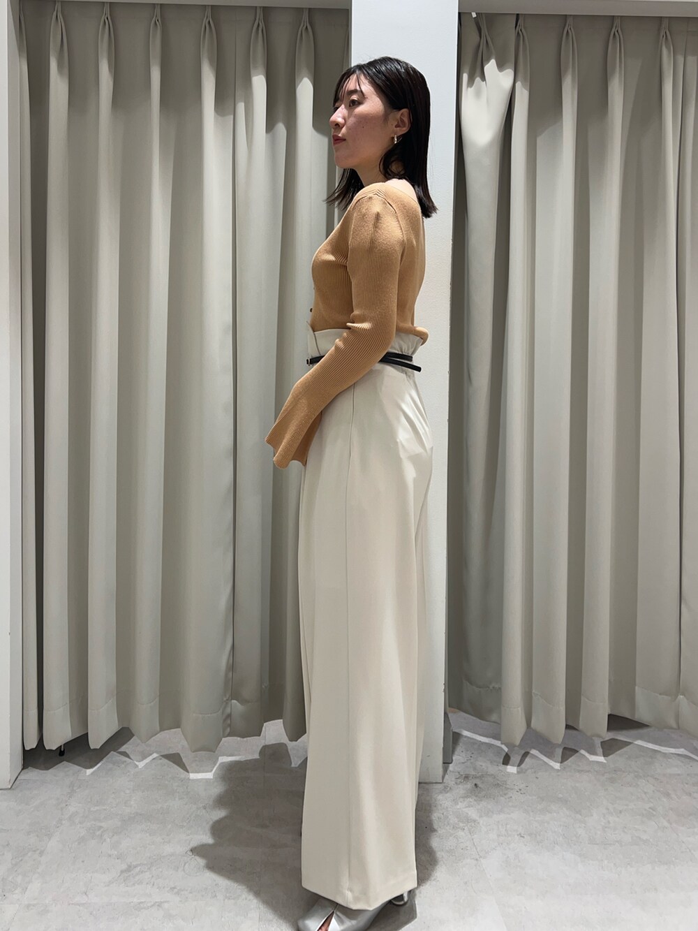 オレンジ系のニット/セーター、シルバー系のパンプス、ホワイト系のその他パンツを着用したレディースの秋コーディネートの2枚目の写真