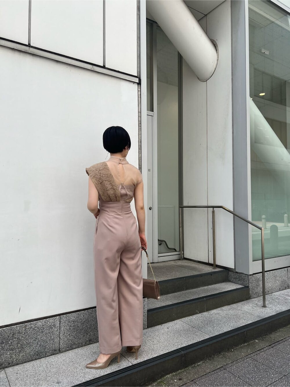 ゴールド系のクラッチバッグ、ベージュ系のパンツドレス、ブラック系のその他トップスを着用したレディースの夏コーディネートの4枚目の写真