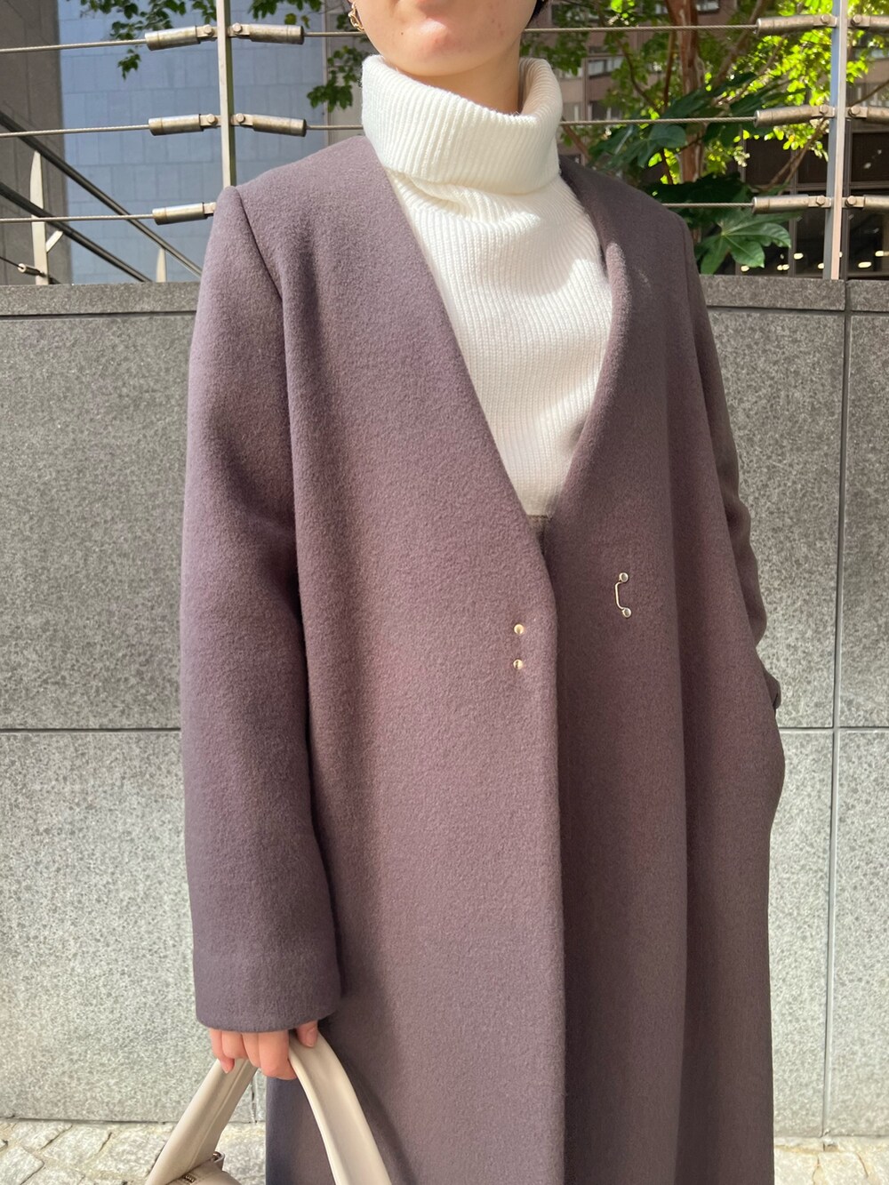 ベージュ系のブーツ、グレー系のスカート、ホワイト系のハンドバッグを着用したレディースの秋コーディネートの4枚目の写真