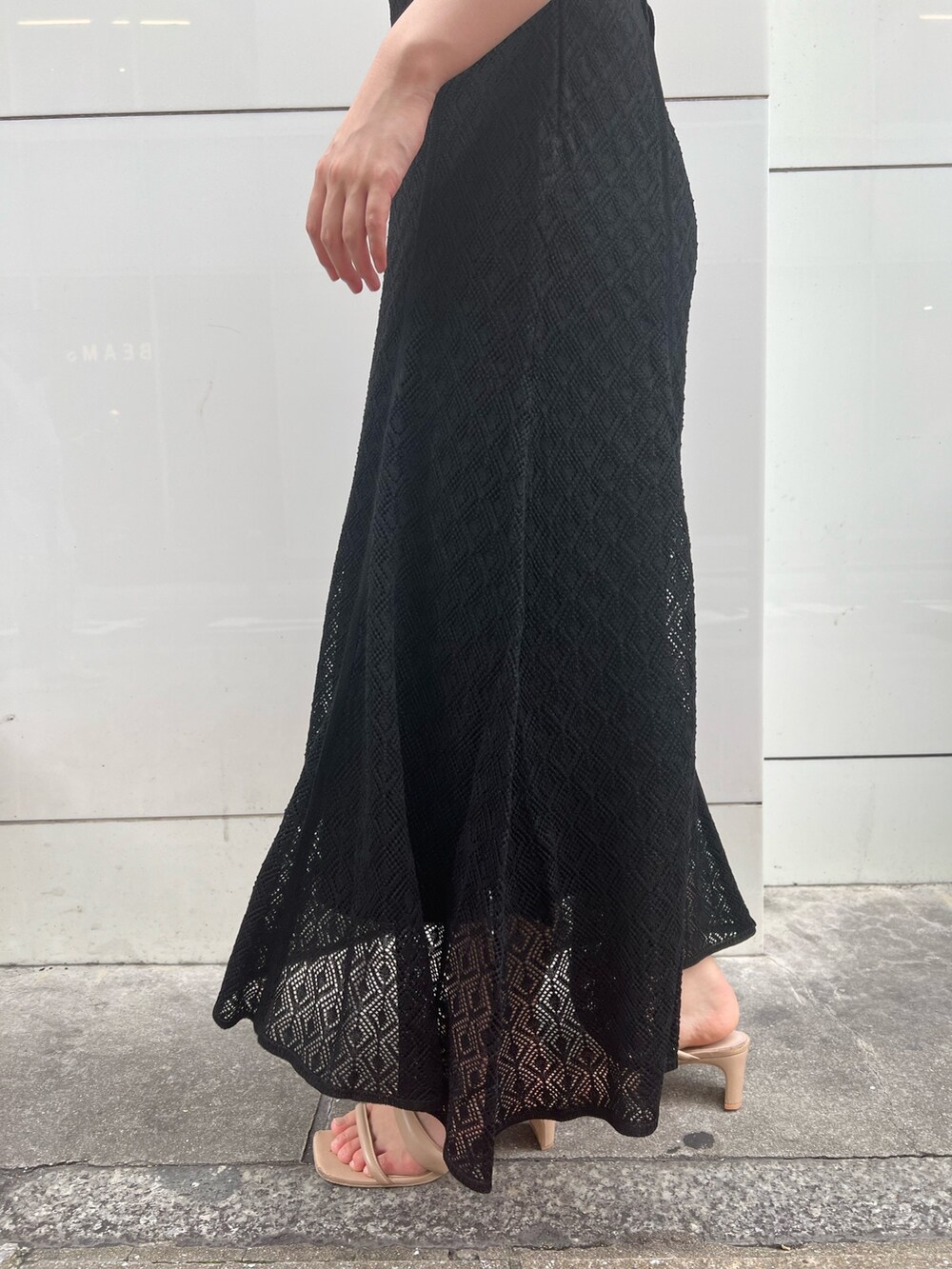 ベージュ系のサンダル、ホワイト系のハンドバッグ、ブラック系のワンピースを着用したレディースの夏コーディネートの8枚目の写真