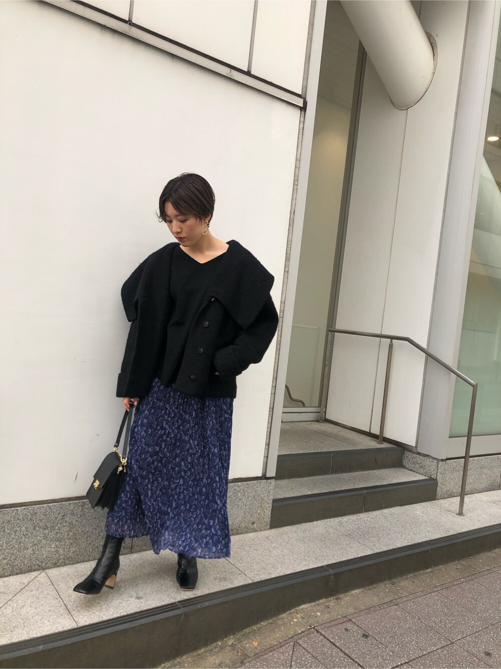 ブラック系のその他アウター、ブラック系のニット/セーター、ブルー系のスカートを着用したレディースの秋コーディネートの2枚目の写真