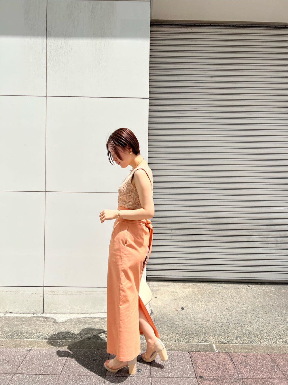 ホワイト系のハンドバッグ、オレンジ系のスカート、その他のパンプスを着用したレディースの春コーディネートの3枚目の写真