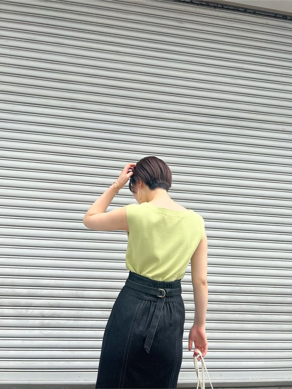 ブルー系のスカート、ベージュ系のサンダル、イエロー系のニット/セーターを着用したレディースの春コーディネートの6枚目の写真