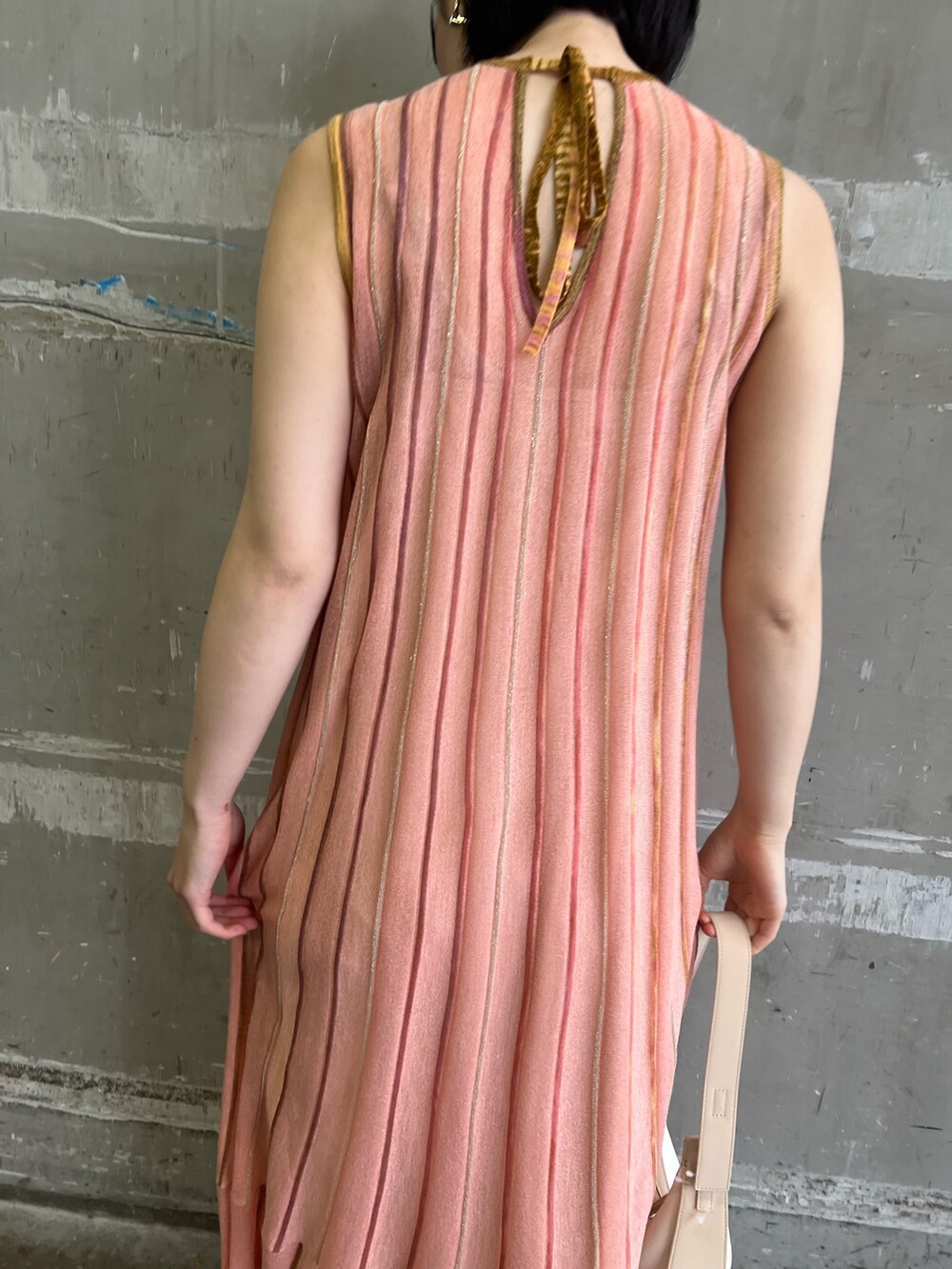 ホワイト系のスニーカー、ベージュ系のハンドバッグ、オレンジ系のワンピースを着用したレディースの春コーディネートの6枚目の写真